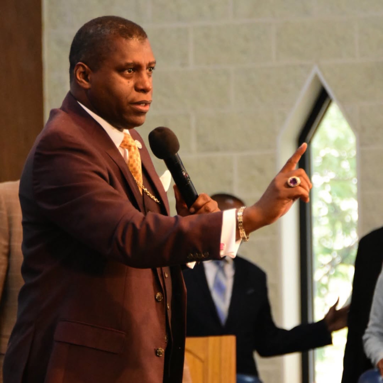 Bishop H. Curtis Douglas preaching beside a sanctuary window.