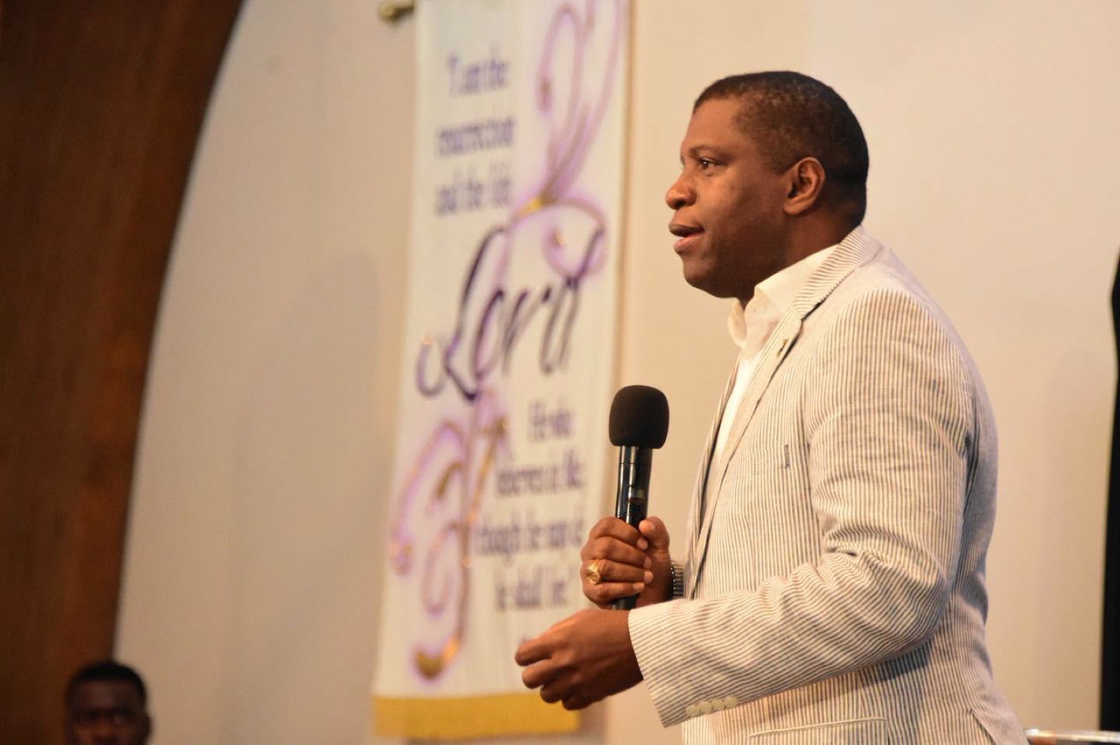A minister preaches beside a “Lord” banner in the sanctuary.