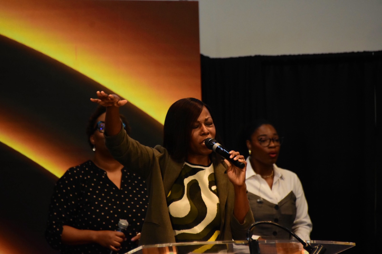 A worship leader lifts her hand as she sings.