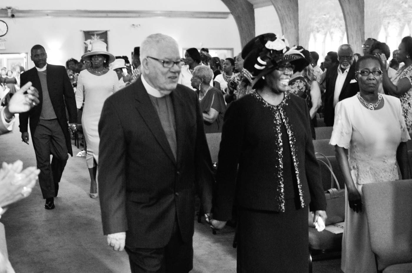 Clergy and members walk the center aisle together during a celebration service as the congregation stands.